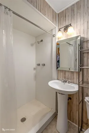 a bathroom with a shower a mirror and a sink