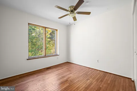 an empty room with wooden floor fan and windows