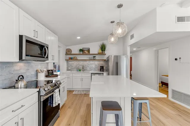 a large kitchen with cabinets a sink dishwasher a stove and a refrigerator with wooden floor