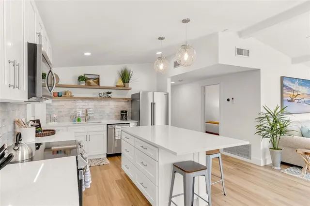 a large white kitchen with lots of counter space and refrigerator