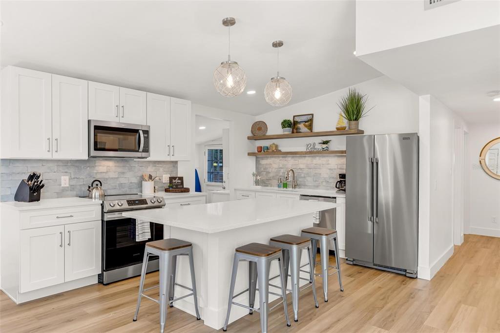 110 Terrapin Road St. Augustine, FL 32086 - Photo 6 of 33 a kitchen with kitchen island a refrigerator stove a sink and dishwasher with wooden floor