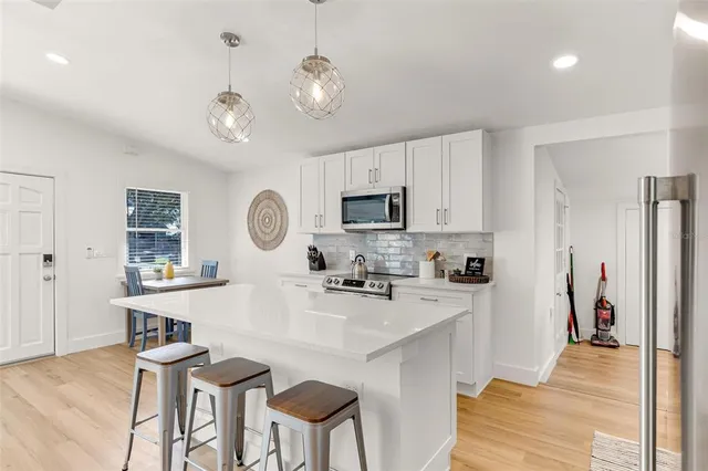 a kitchen with stainless steel appliances granite countertop a stove top oven a refrigerator a sink and dishwasher with wooden floor