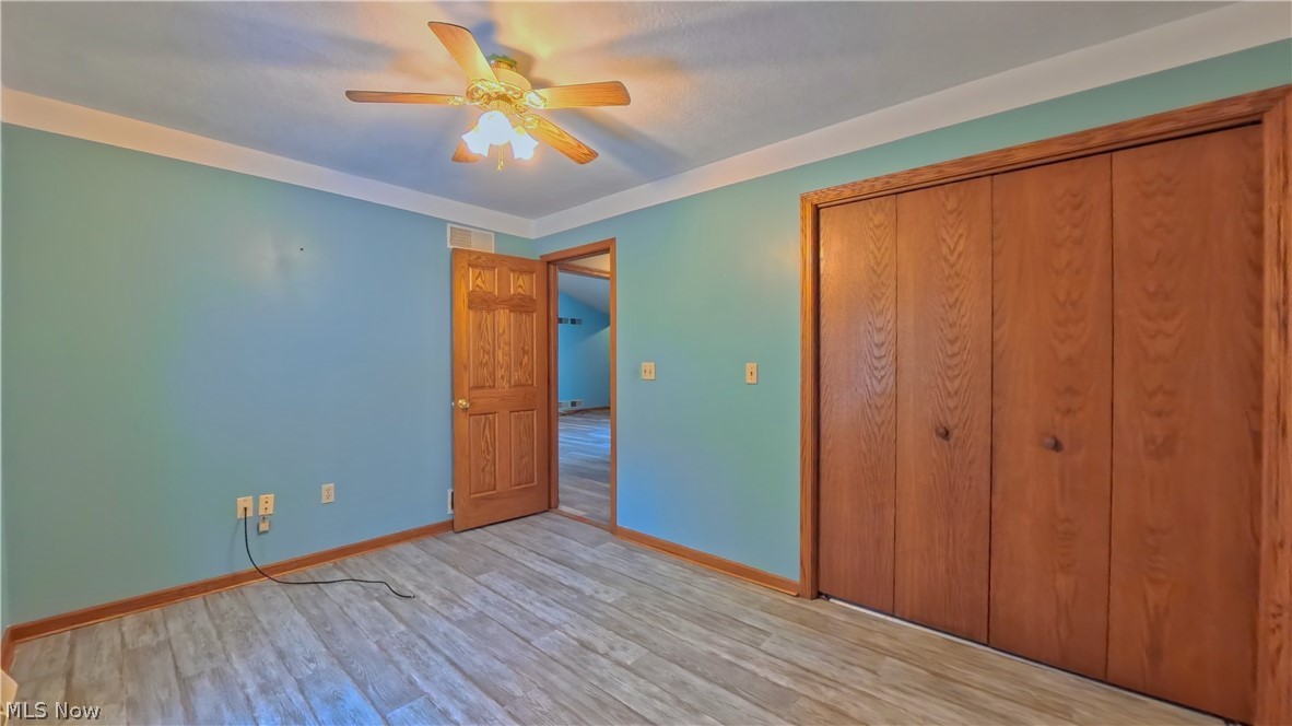 48276 Dyke Road Negley, OH 44441 - Photo 17 of 30 Unfurnished bedroom with light wood-style flooring, ceiling fan, and a closet