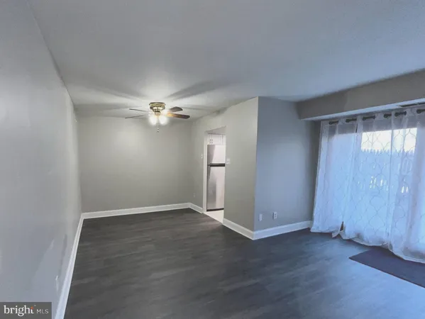 an empty room with wooden floor closet and windows