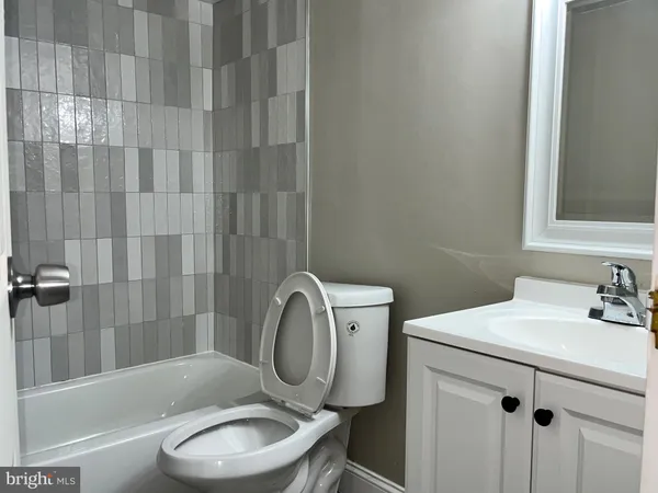 a bathroom with a bathtub shower sink mirror vanity and toilet