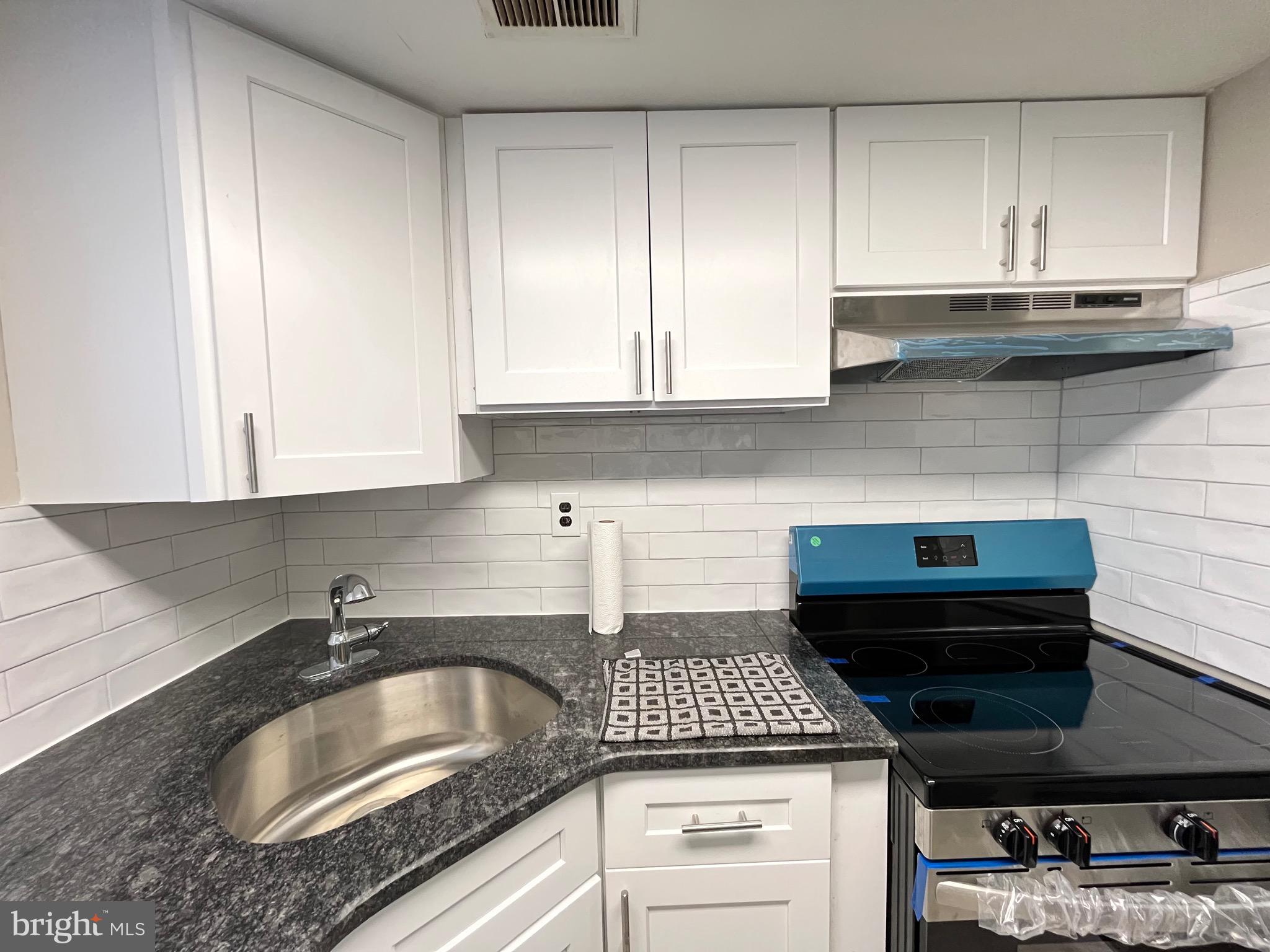 8030 Ditman Street, Unit 44H Philadelphia, PA 19136 - Photo 22 of 25 a kitchen with granite countertop a sink stove and cabinets