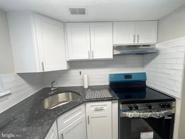 a kitchen with a stove and white cabinets