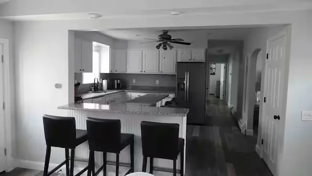 a kitchen with stainless steel appliances granite countertop a table chairs refrigerator and sink