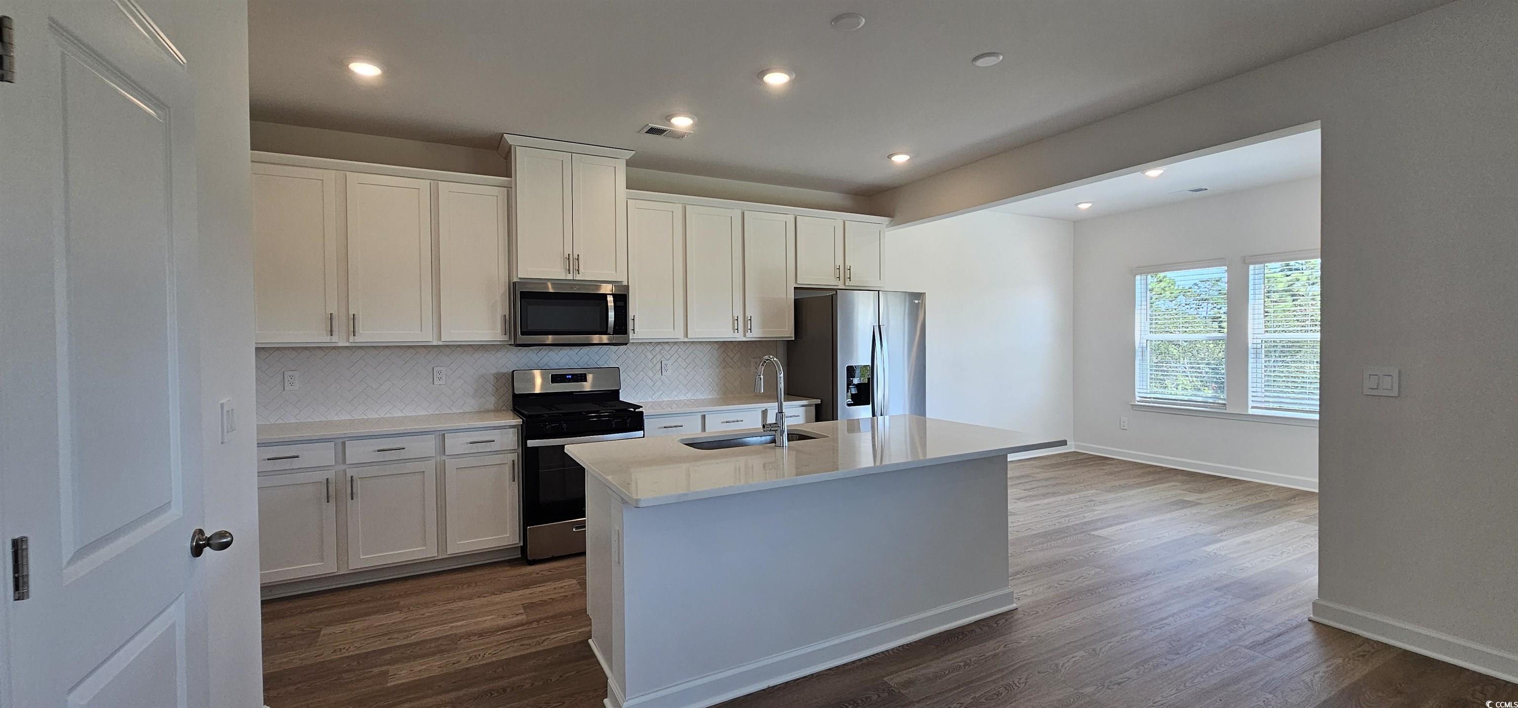 8233 Vibrant Loop Columbia, SC 29209 - Photo 6 of 40 Kitchen featuring tasteful backsplash, stainless steel appliances, white cabinets, a center island with sink, and recessed lighting