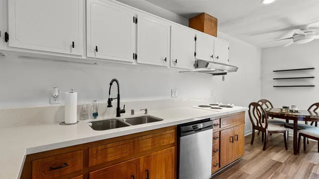 a kitchen with stainless steel appliances granite countertop a sink stove and white cabinets with wooden floor