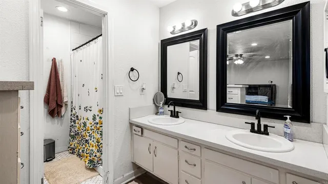 a bathroom with a double vanity sink mirror and shower