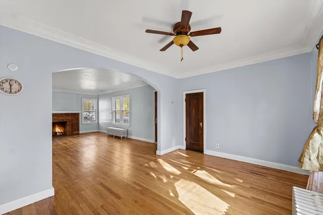 a view of an empty room with window and wooden floor