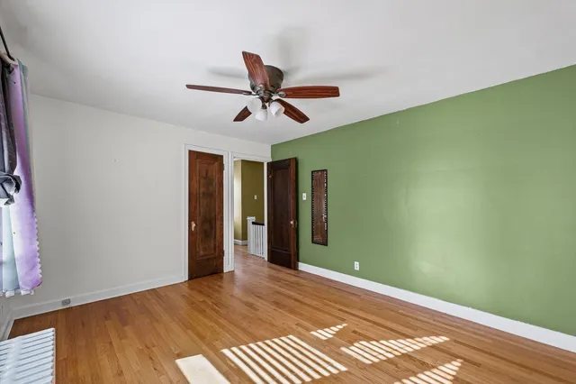 a view of a room with a ceiling fan and hardwood floor