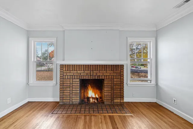 an empty room with windows a fireplace and wooden floor
