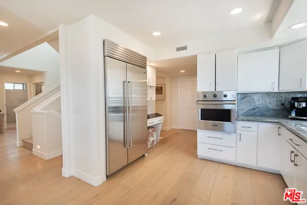 a kitchen with stainless steel appliances kitchen island granite countertop a refrigerator and a sink