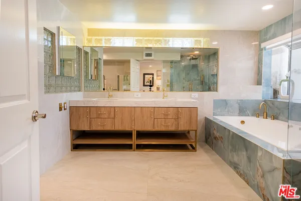 a bathroom with a tub a double vanity sink and mirror