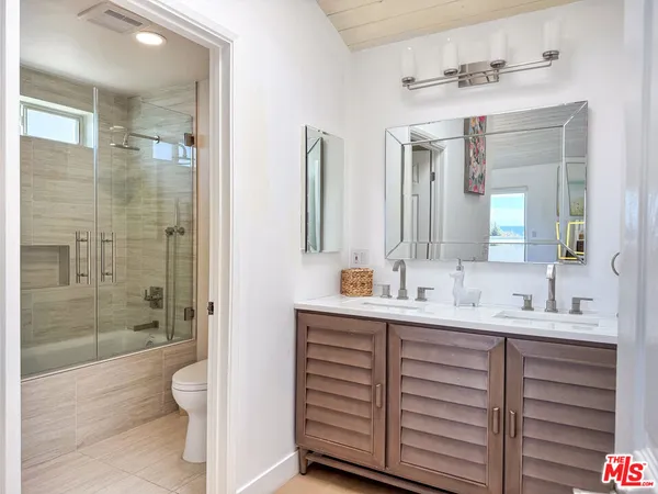 a bathroom with a double vanity sink mirror and shower