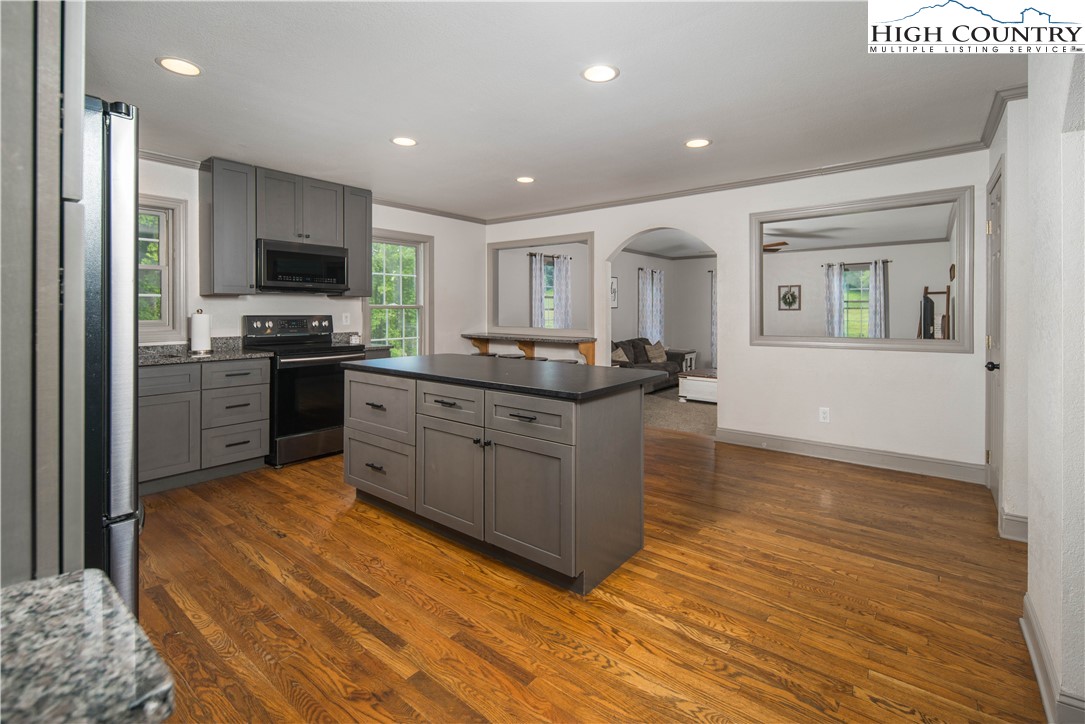 1527 Mabel School Road Zionville, NC 28698 - Photo 12 of 49 a kitchen with stainless steel appliances granite countertop a stove top oven a sink dishwasher a refrigerator and a dining table with wooden floor