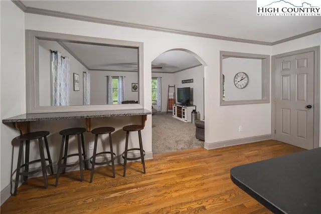 a kitchen with stainless steel appliances granite countertop a stove top oven a sink dishwasher a refrigerator and a dining table with wooden floor