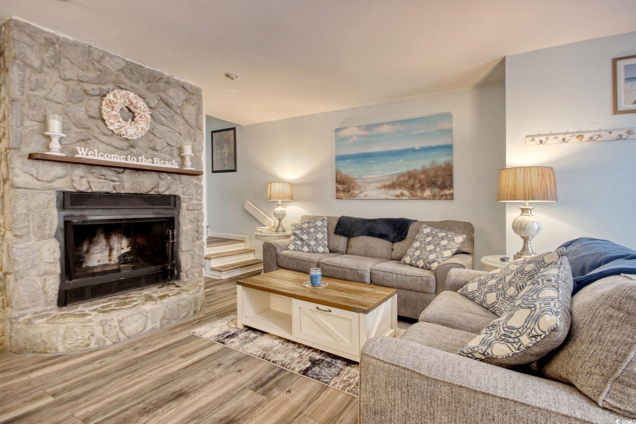 Living room featuring a stone fireplace and wood finished floors
