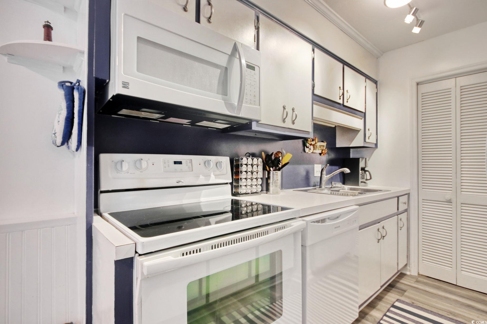 Kitchen featuring white appliances, light countertops, and light wood-style floors