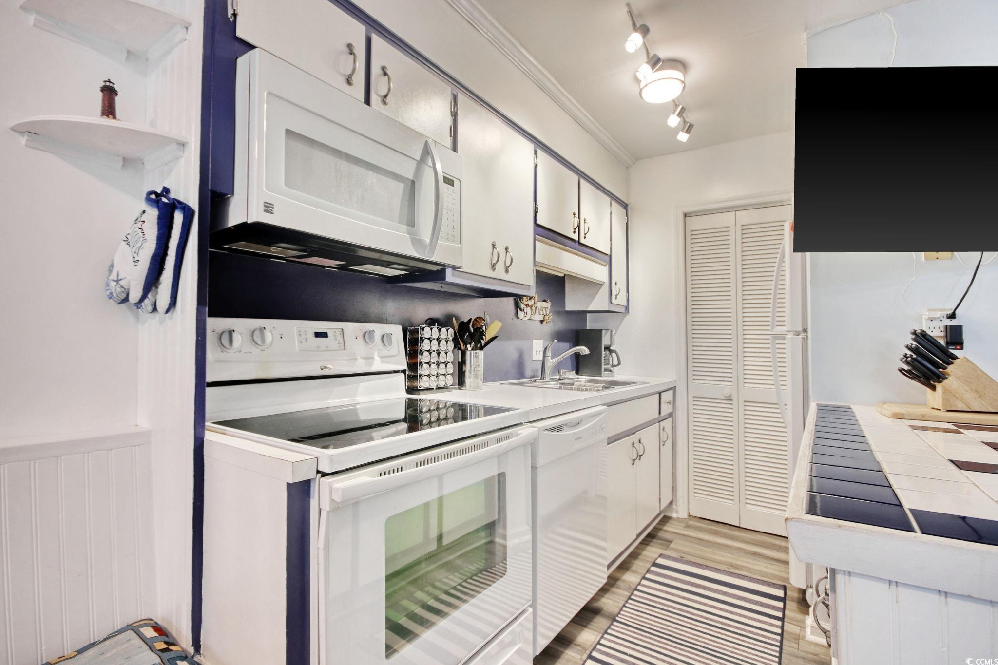 Kitchen with white appliances, tile countertops, white cabinets, and ornamental molding