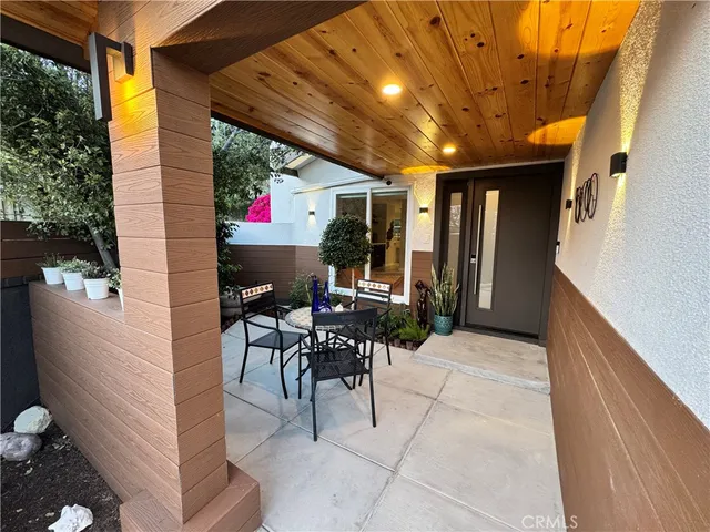 a patio with table and chairs and potted plants