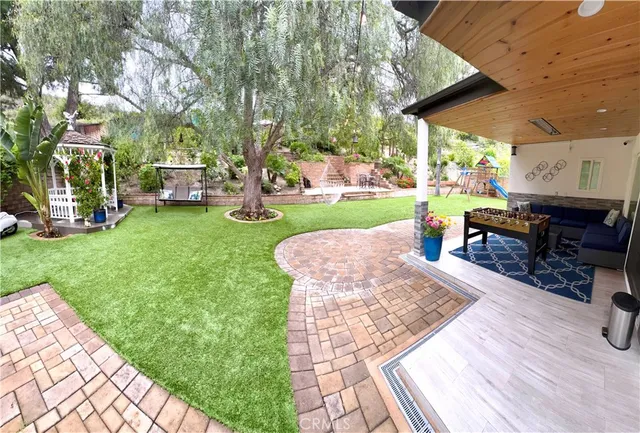 a view of a backyard with table and chairs potted plants and a large tree