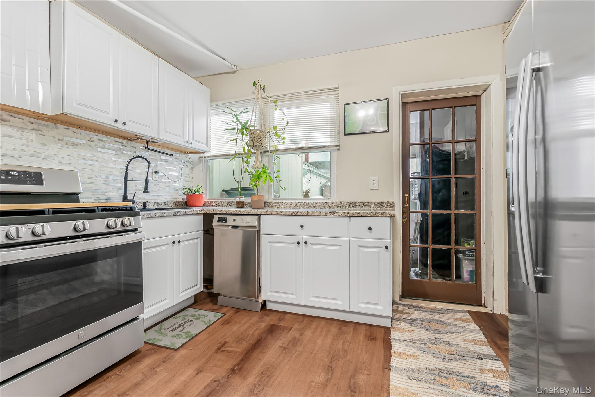 85-14 Sutter Avenue Queens, NY 11417 - Photo 13 of 27 Kitchen with stainless steel appliances, white shaker style cabinets, and light wood-style floors
