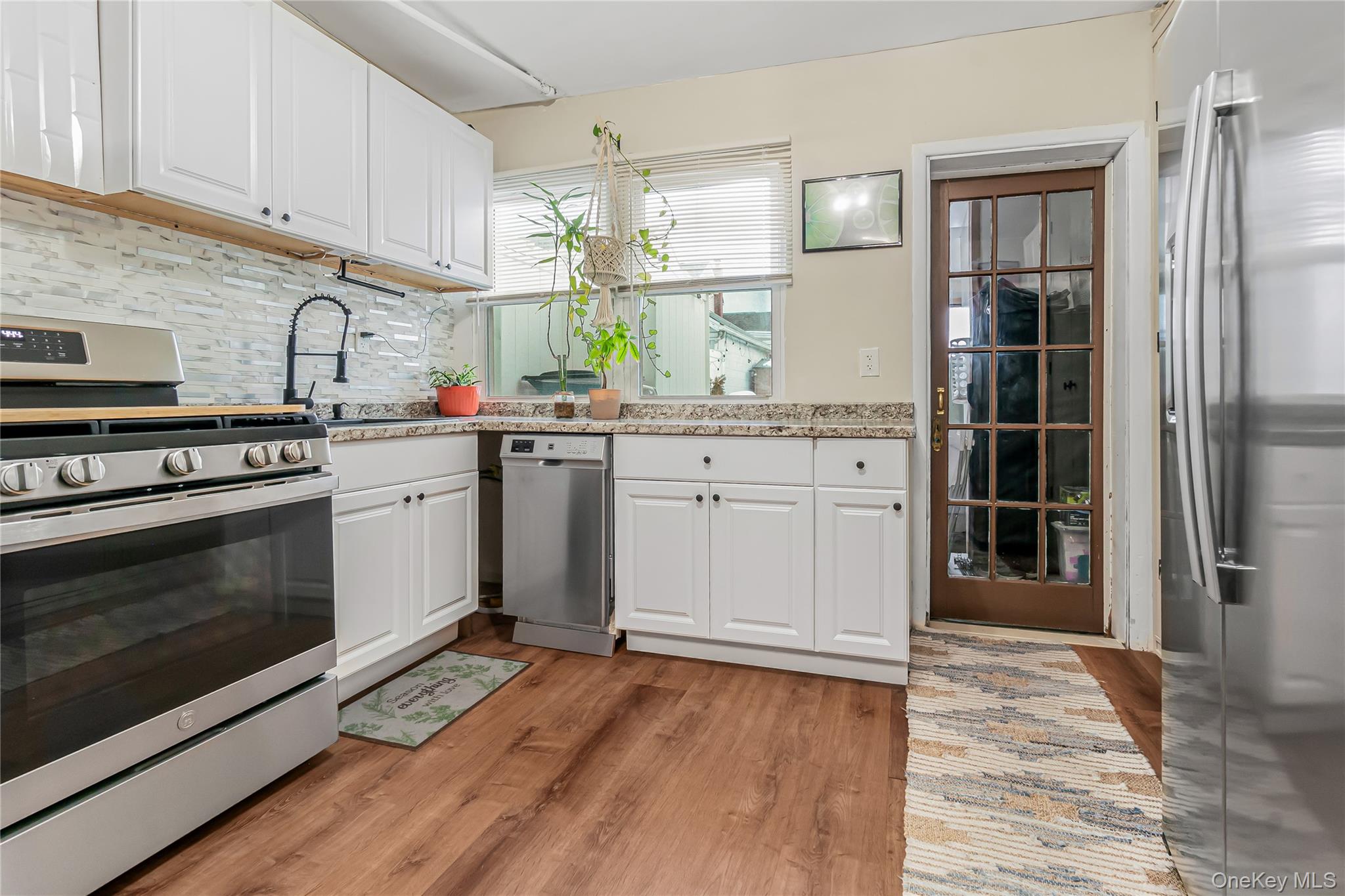 85-14 Sutter Avenue Queens, NY 11417 - Photo 14 of 27 Kitchen featuring stainless steel appliances, white Shaker style cabinetry, and light wood-type flooring