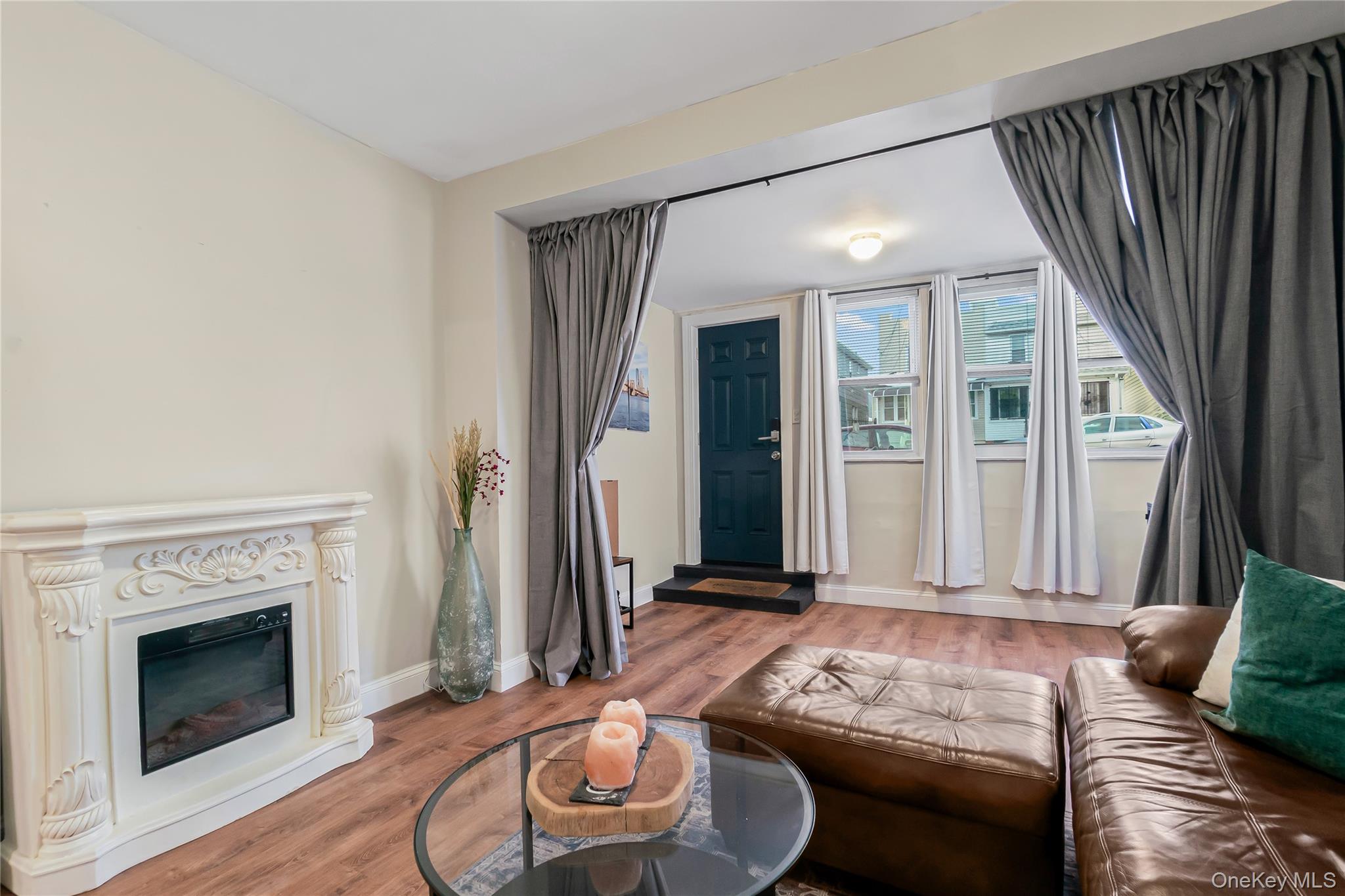 85-14 Sutter Avenue Queens, NY 11417 - Photo 4 of 27 Living room featuring wood finished floors and a glass covered fireplace