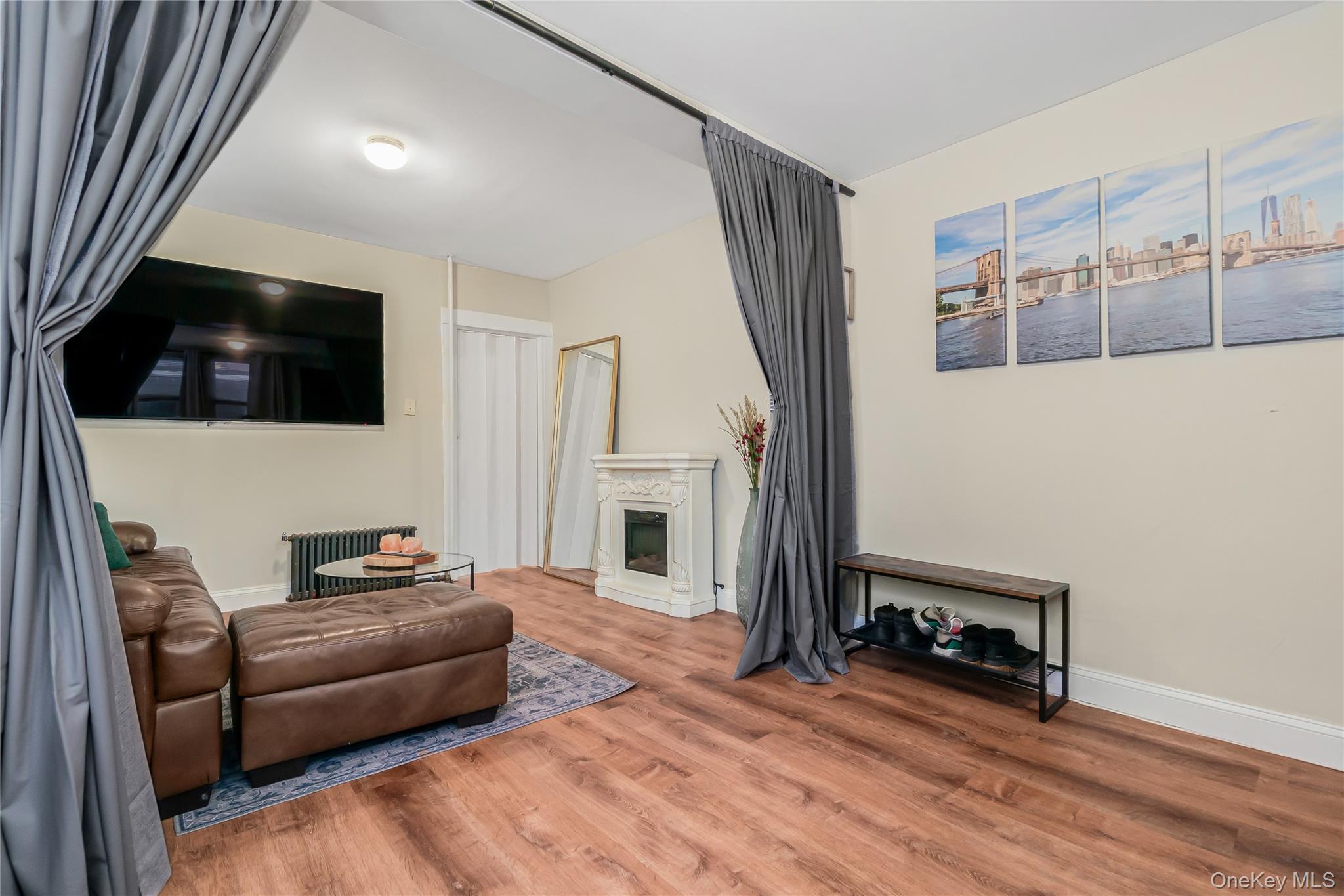 85-14 Sutter Avenue Queens, NY 11417 - Photo 9 of 27 Living room with wood finished floors, a glass covered fireplace, and radiator heating unit