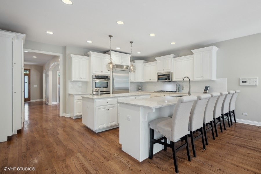 438 West 3rd Street Elmhurst, IL 60126 - Photo 9 of 43 a large kitchen with kitchen island a dining table chairs and white cabinets
