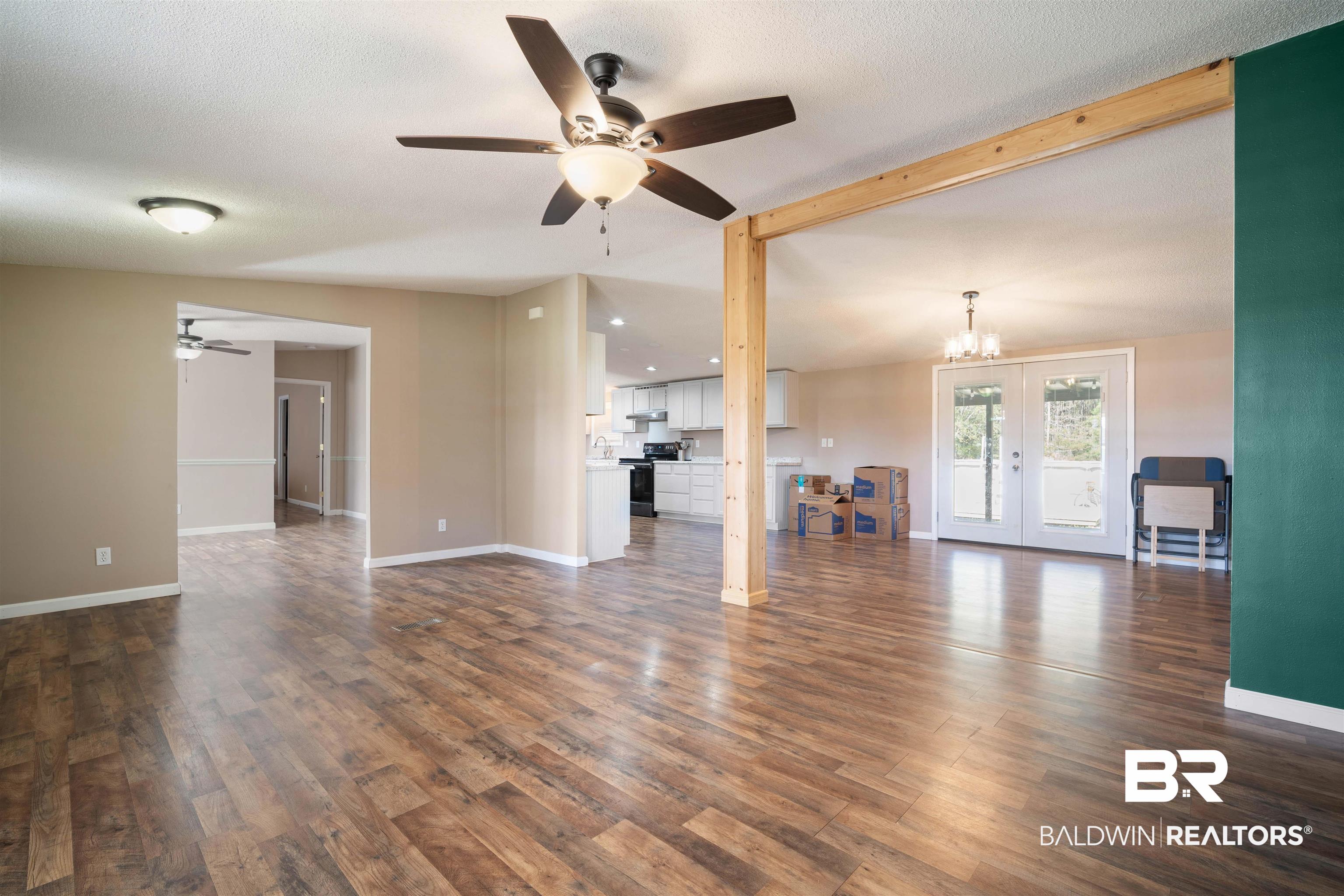 9011 Wilmer Georgetown Road Wilmer, AL 36587 - Photo 7 of 34 Unfurnished living room with baseboards, dark wood-style floors, french doors, and ceiling fan with notable chandelier