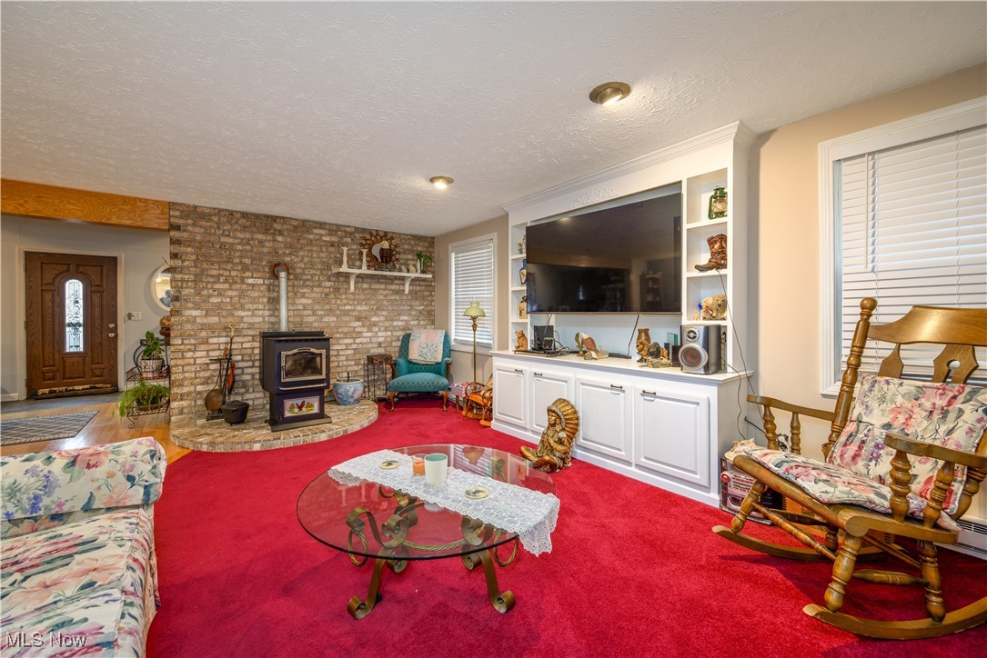 17080 Heiser Road Berlin Center, OH 44401 - Photo 27 of 35 Living room with carpet, a healthy amount of sunlight, a wood stove, and a textured ceiling