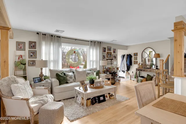 a living room with furniture large window and wooden floor
