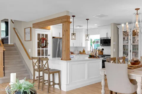 a large white kitchen with sink a refrigerator and chairs