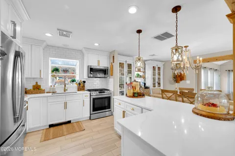 a kitchen with stainless steel appliances kitchen island granite countertop a sink a stove and a wooden floor