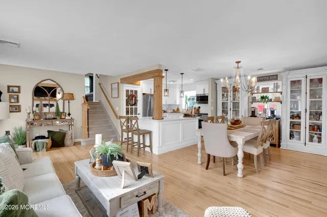a living room with furniture a dining table with wooden floor and a view of kitchen