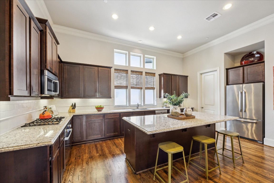 9634 Kings Cross Station Houston, TX 77045 - Photo 6 of 24 KITCHEN - Bright and open kitchen features a large granite island, stainless Bosch appliances, under cabinet lighting, subway tile backsplash and a walk-in pantry.