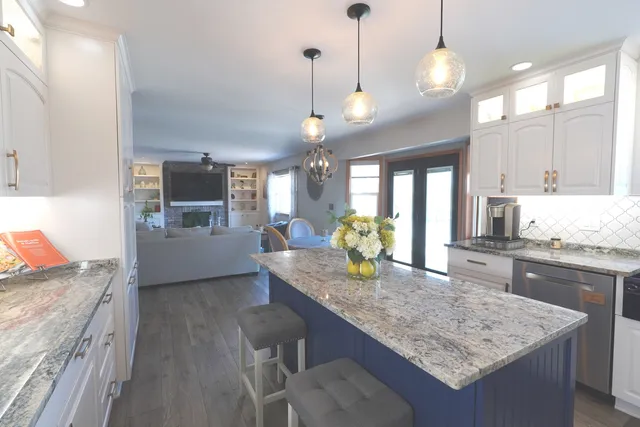 a kitchen with kitchen island granite countertop a sink cabinets and window