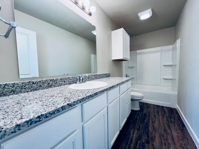 a bathroom with a granite countertop double vanity sink and mirror
