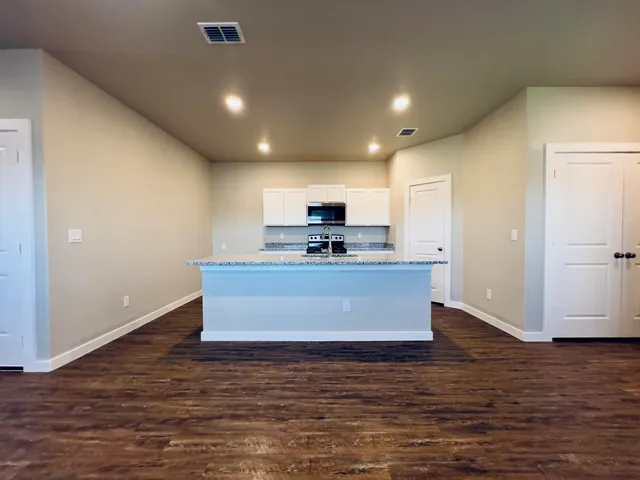 a view of kitchen with stainless steel appliances granite countertop a large counter top and a wooden floor