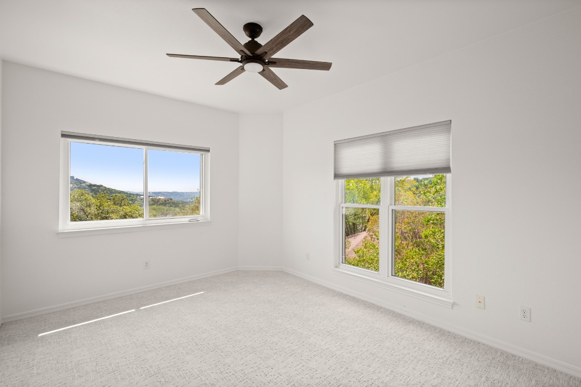 4906 Bob Cat Run Austin, TX 78731 - Photo 16 of 37 Unfurnished room featuring carpet flooring, healthy amount of natural light, and a ceiling fan