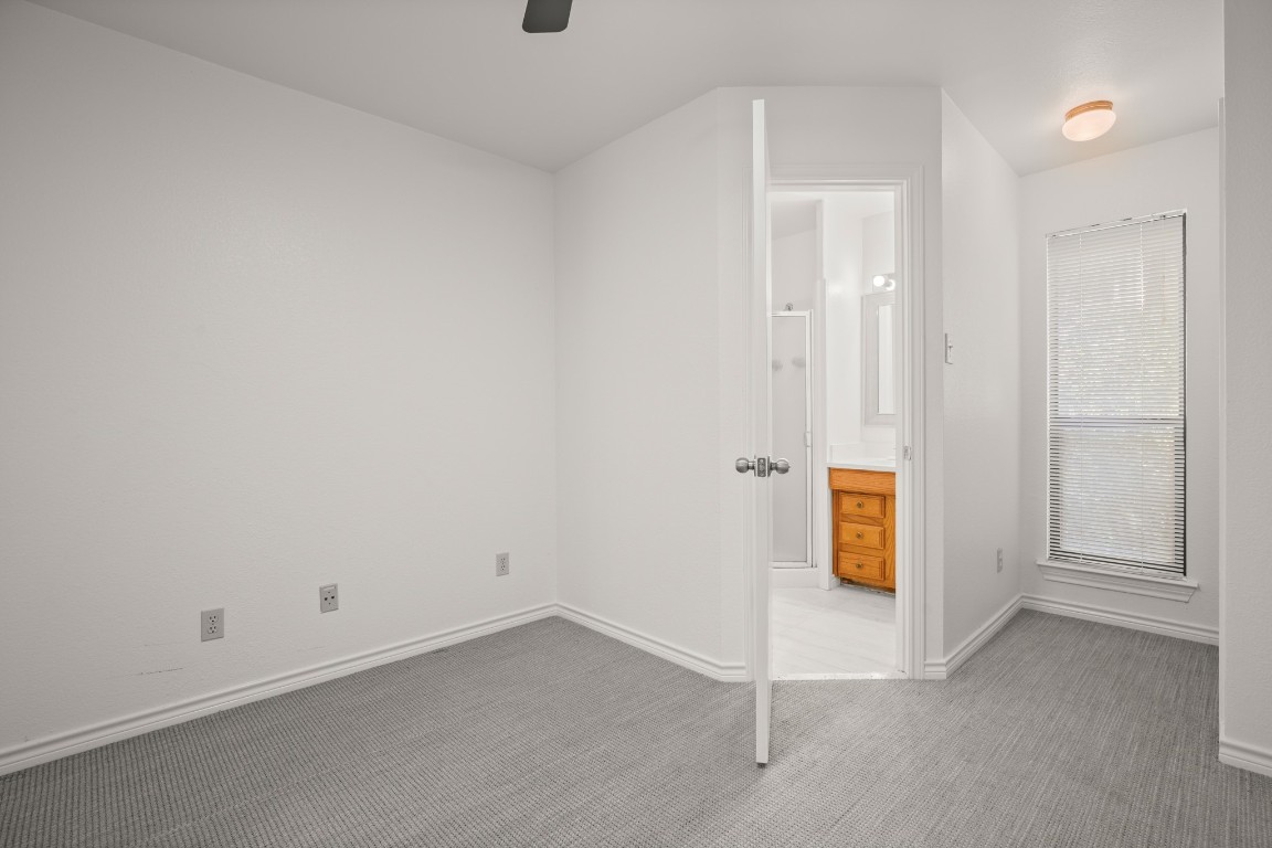 4906 Bob Cat Run Austin, TX 78731 - Photo 26 of 37 Unfurnished bedroom with carpet flooring, connected bathroom, and ceiling fan