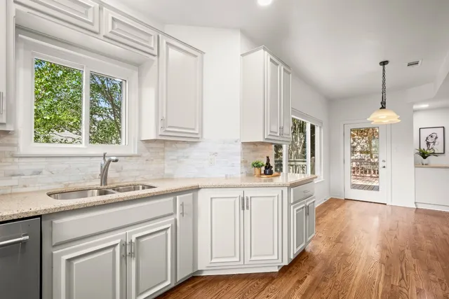 a kitchen with granite countertop a sink cabinets stainless steel appliances and a large window