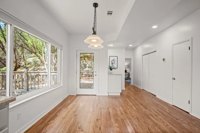 a view of an empty room with wooden floor and a window