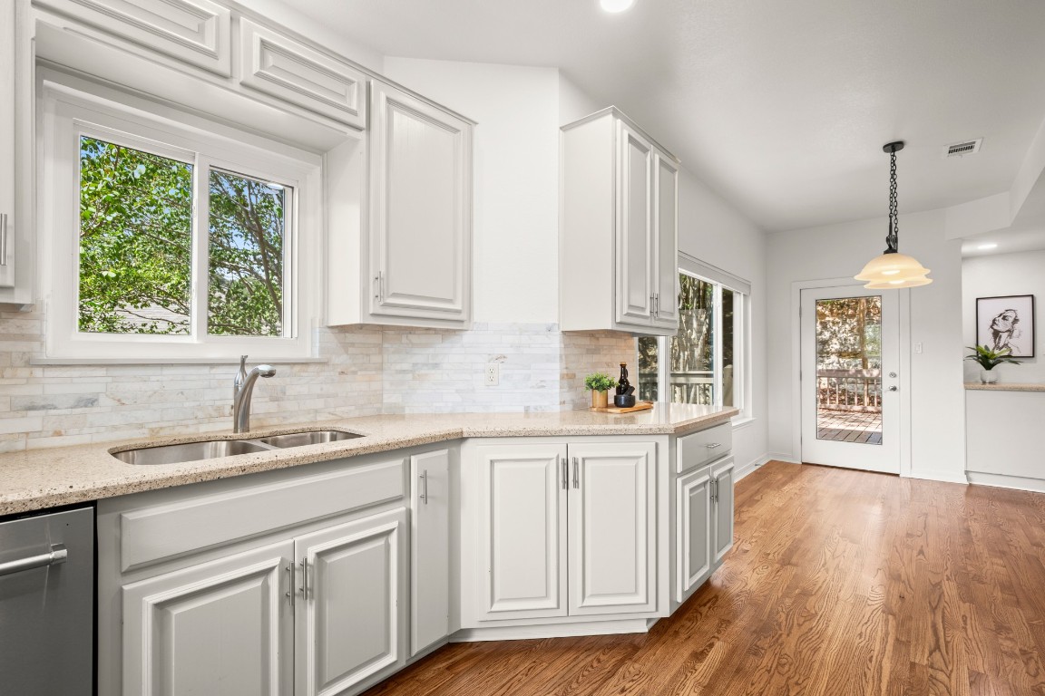 4906 Bob Cat Run Austin, TX 78731 - Photo 8 of 37 Kitchen featuring pendant lighting, white cabinets, light stone countertops, backsplash, and light wood finished floors