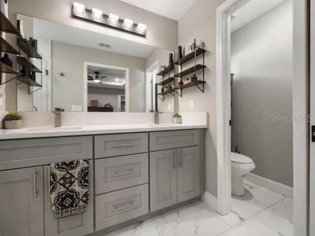 a bathroom with a granite countertop sink toilet and mirror