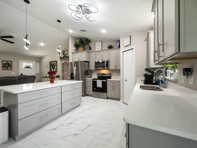 a kitchen with stainless steel appliances kitchen island granite countertop a refrigerator oven a sink a dining table and chairs with wooden floor